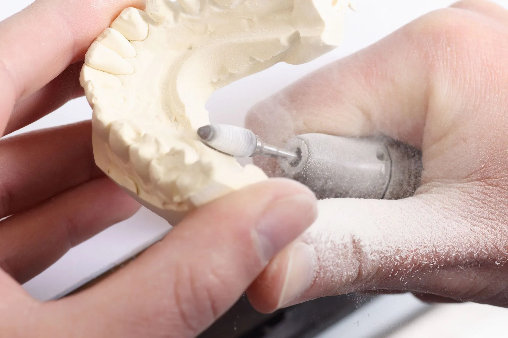 Zahntechniker bearbeitet ein Gipsmodell von Hand im Labor in Thun